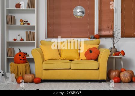 Stilvolles Wohnzimmer mit Diskokugel und gelbem Sofa für Halloween-Party Stockfoto