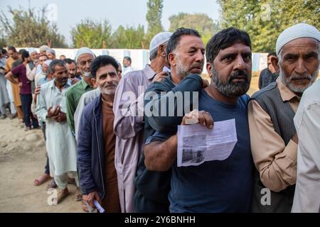 Srinagar, Indien. September 2024. Kaschmir-Wähler warten in einer Warteschlange, um ihre Stimmzettel vor dem Wahlhaus abzugeben, während der zweiten Phase der Parlamentswahlen in Jammu und Kaschmir am Stadtrand von Srinagar. Dies sind die ersten Kommunalwahlen seit einem Jahrzehnt und die ersten, seit Neu-Delhi 2019 den halbautonomen Status der Region widerrief und sie unter direkte Herrschaft stellte. Fast neun Millionen Menschen sind registriert, um in der umstrittenen Region zu wählen, die traditionell für Boykotte aus Protest gegen die indische Herrschaft bekannt ist. Quelle: SOPA Images Limited/Alamy Live News Stockfoto