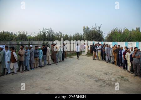 Srinagar, Indien. September 2024. Kaschmir-Wähler warten in Warteschlangen, um ihre Stimmzettel vor dem Wahlhaus abzugeben, während der zweiten Phase der Parlamentswahlen in Jammu und Kaschmir am Stadtrand von Srinagar. Dies sind die ersten Kommunalwahlen seit einem Jahrzehnt und die ersten, seit Neu-Delhi 2019 den halbautonomen Status der Region widerrief und sie unter direkte Herrschaft stellte. Fast neun Millionen Menschen sind registriert, um in der umstrittenen Region zu wählen, die traditionell für Boykotte aus Protest gegen die indische Herrschaft bekannt ist. Quelle: SOPA Images Limited/Alamy Live News Stockfoto