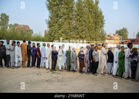 Srinagar, Indien. September 2024. Kaschmir-Wähler warten in einer Warteschlange, um ihre Stimmzettel vor dem Wahlhaus abzugeben, während der zweiten Phase der Parlamentswahlen in Jammu und Kaschmir am Stadtrand von Srinagar. Dies sind die ersten Kommunalwahlen seit einem Jahrzehnt und die ersten, seit Neu-Delhi 2019 den halbautonomen Status der Region widerrief und sie unter direkte Herrschaft stellte. Fast neun Millionen Menschen sind registriert, um in der umstrittenen Region zu wählen, die traditionell für Boykotte aus Protest gegen die indische Herrschaft bekannt ist. Quelle: SOPA Images Limited/Alamy Live News Stockfoto