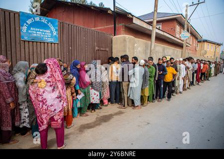 Srinagar, Indien. September 2024. Kaschmir-Wähler warten in einer Warteschlange, um ihre Stimmzettel vor dem Wahlhaus abzugeben, während der zweiten Phase der Parlamentswahlen in Jammu und Kaschmir am Stadtrand von Srinagar. Dies sind die ersten Kommunalwahlen seit einem Jahrzehnt und die ersten, seit Neu-Delhi 2019 den halbautonomen Status der Region widerrief und sie unter direkte Herrschaft stellte. Fast neun Millionen Menschen sind registriert, um in der umstrittenen Region zu wählen, die traditionell für Boykotte aus Protest gegen die indische Herrschaft bekannt ist. Quelle: SOPA Images Limited/Alamy Live News Stockfoto