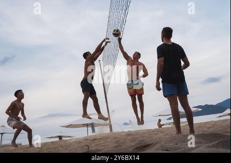 Teams mit multinationalen Spielern spielen im Sommer Beachvolleyball am Strand am Meer in Vietnam. Nha Trang, Vietnam - 4. August 2024 Stockfoto