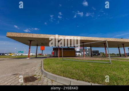 Inaktive und verlassene Tankstelle, inaktive Spender, verschobene Fenster, umzäunter Bereich, alter Bahnhof im Stadtzentrum an der Schnellstraße Stockfoto