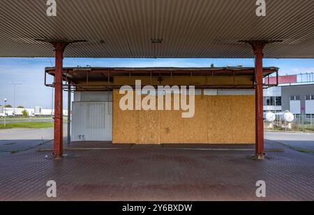 Inaktive und verlassene Tankstelle, inaktive Spender, verschobene Fenster, umzäunter Bereich, alter Bahnhof im Stadtzentrum an der Schnellstraße Stockfoto