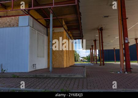 Inaktive und verlassene Tankstelle, inaktive Spender, verschobene Fenster, umzäunter Bereich, alter Bahnhof im Stadtzentrum an der Schnellstraße Stockfoto