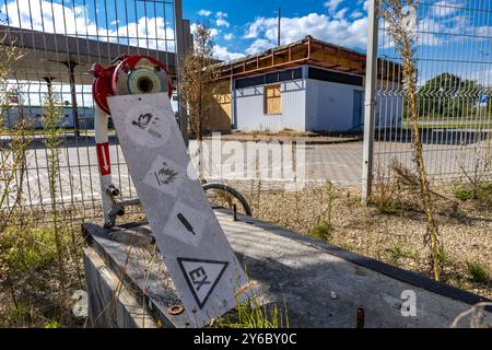 Inaktive und verlassene Tankstelle, inaktive Spender, verschobene Fenster, umzäunter Bereich, alter Bahnhof im Stadtzentrum an der Schnellstraße Stockfoto