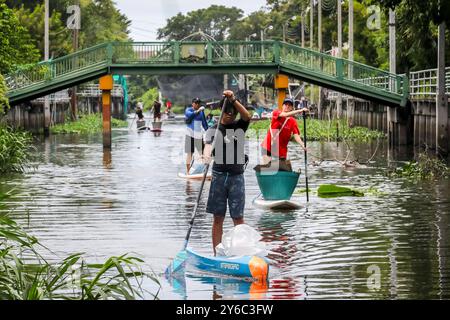 Freiwillige Kanalreinigung in Samutprakarn, Thailand Freiwillige auf Starboard SUP Stand-up Paddle Boards sammeln Müll entlang eines Kanals während eines von Steuerboard organisierten Aufräumtages in Samut Prakan, am Stadtrand von Bangkok, Thailand, am 21. September 2024. Die Freiwilligen, die an der Säuberung teilnahmen, wurden in zwei Gruppen aufgeteilt, in denen die größere Gruppe Müll hauptsächlich Plastikmüll aus dem Kanal sammelte, während die andere Gruppe Müll sammelte, der in nahegelegenen Gassen entsorgt wurde. Steuerbord bietet regelmäßig SUP-Bretter für Kanalreinigungen und hilft dabei, Gemeinden zusammenzubringen, um Abfall zu reinigen und zu reduzieren. Sie machen das über Stockfoto