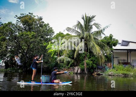 Freiwillige Kanalreinigung in Samutprakarn, Thailand Freiwillige auf Starboard SUP Stand-up Paddle Boards sammeln Müll entlang eines Kanals während eines von Steuerboard organisierten Aufräumtages in Samut Prakan, am Stadtrand von Bangkok, Thailand, am 21. September 2024. Die Freiwilligen, die an der Säuberung teilnahmen, wurden in zwei Gruppen aufgeteilt, in denen die größere Gruppe Müll hauptsächlich Plastikmüll aus dem Kanal sammelte, während die andere Gruppe Müll sammelte, der in nahegelegenen Gassen entsorgt wurde. Steuerbord bietet regelmäßig SUP-Bretter für Kanalreinigungen und hilft dabei, Gemeinden zusammenzubringen, um Abfall zu reinigen und zu reduzieren. Sie machen das über Stockfoto