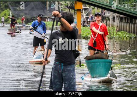 Freiwillige Kanalreinigung in Samutprakarn, Thailand Freiwillige auf Starboard SUP Stand-up Paddle Boards sammeln Müll entlang eines Kanals während eines von Steuerboard organisierten Aufräumtages in Samut Prakan, am Stadtrand von Bangkok, Thailand, am 21. September 2024. Die Freiwilligen, die an der Säuberung teilnahmen, wurden in zwei Gruppen aufgeteilt, in denen die größere Gruppe Müll hauptsächlich Plastikmüll aus dem Kanal sammelte, während die andere Gruppe Müll sammelte, der in nahegelegenen Gassen entsorgt wurde. Steuerbord bietet regelmäßig SUP-Bretter für Kanalreinigungen und hilft dabei, Gemeinden zusammenzubringen, um Abfall zu reinigen und zu reduzieren. Sie machen das über Stockfoto