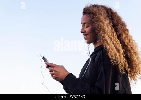 lateinische Athletin, die Musik am Handy hört Stockfoto