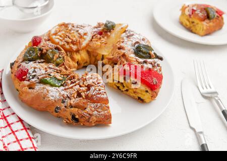 Ein festlicher, kranzförmiger Kuchen mit kandierten Früchten, Nüssen und Zucker, auf einem weißen Teller Stockfoto