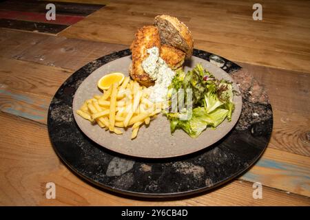 Ein köstlicher Teller mit geräuchertem Haddock Fish Finger Sandwich mit Pommes und Tartarsauce auf einem hölzernen Küchentisch Stockfoto