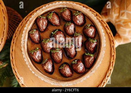 Ein Blick von oben auf ein Holztablett gefüllt mit Erdbeeren mit Schokoladenüberzug, die ordentlich in einem Korb angeordnet sind. Stockfoto