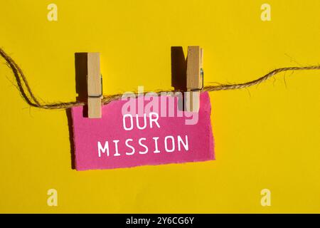 Unsere Botschaft auf gerissenem rosafarbenem Papier mit gelbem Hintergrund. Konzeptionelles unser Missionssymbol. Kopierbereich. Stockfoto