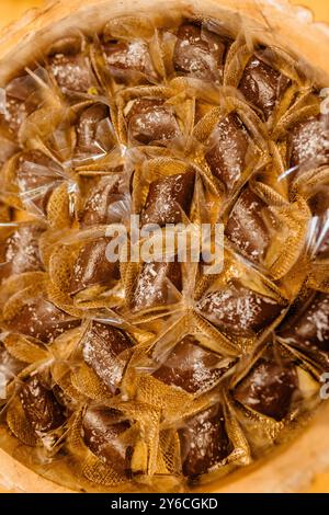 Nahaufnahme eines Korbs, der mit einzeln verpackten Schokoladenbonbons gefüllt ist, wodurch Textur und Verpackung hervorgehoben werden. Stockfoto