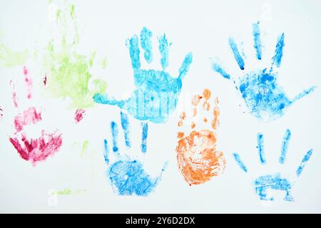 Helle Kinderhandabdrücke mit blauer, grüner, roter und oranger Farbe auf weißem Hintergrund Stockfoto