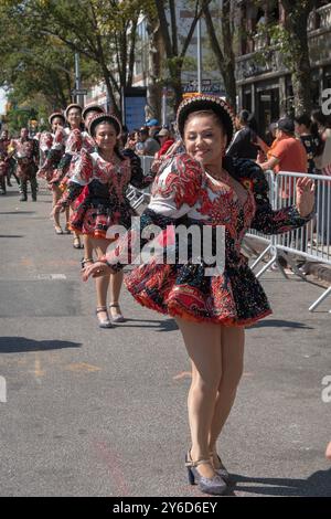 Eine glückliche peruanische junge Dame aus Amerika marschiert und tanzt in einem farbenfrohen Kostüm mit der Gruppe bei der Queens Hispanic Day Parade 2024 in Jackson Heights. Stockfoto