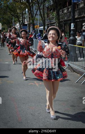 Eine glückliche peruanische junge Dame aus Amerika marschiert und tanzt in einem farbenfrohen Kostüm mit der Gruppe bei der Queens Hispanic Day Parade 2024 in Jackson Heights. Stockfoto