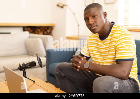 Zu Hause, Aufnahme Podcast, afroamerikaner sitzt auf Couch mit Mikrofon und Laptop Stockfoto