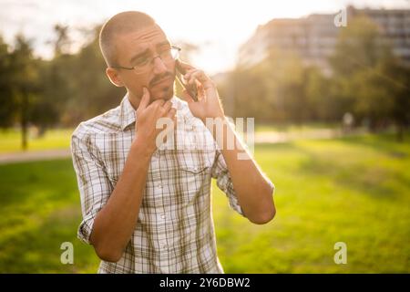 Porträt eines besorgten Erwachsenen im Park, der telefoniert. Stockfoto