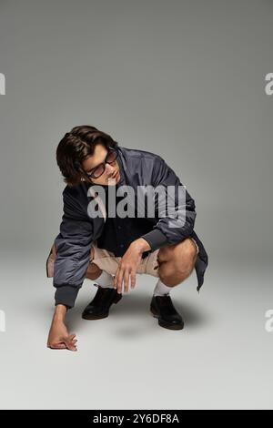 Ein junger Mann posiert selbstbewusst in einem herbstlichen Outfit und unterstreicht sein stilvolles Flair und seinen einzigartigen Ausdruck. Stockfoto