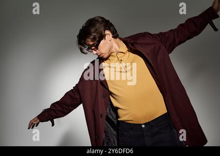 Ein junger Mann in einem stilvollen Herbstoutfit zeigt eine selbstbewusste Pose und unterstreicht so sein Gespür für Mode und Haltung. Stockfoto