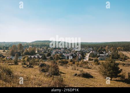 Schöner Sommersonnenaufgang in den Bergen. Wellige Felder und Dorf. Panoramablick mit ländlicher Schotterstraße zwischen Frühlingsfeldern und alten Eichen und Stockfoto