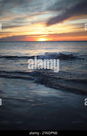 Ein ruhiger Sonnenuntergang mit sanften Wellen und einem farbenfrohen Himmel an der kroatischen Küste. Stockfoto