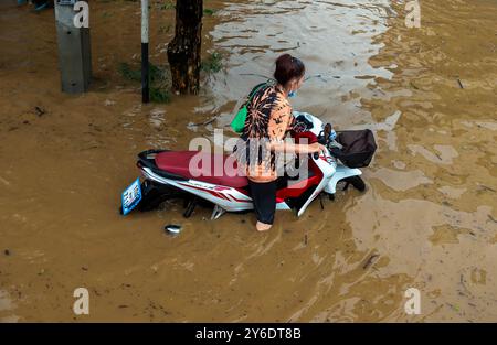 Chiang Mai, Thailand. September 2024. Eine Frau, die auf einer überfluteten Straße im Gebiet von Chang Khlan mit einem Motorrad unterwegs war, da der Ping-Fluss nach anhaltendem Regen in Chiang Mai in Stadtgebiete überfließt. Die Überschwemmungen im Stadtgebiet von Chiang Mai, insbesondere im Bezirk Chang Khlan, sind auf mehrere Tage in Folge von starken Regenfällen zurückzuführen, die den Wasserstand im Ping River ansteigen und seine Ufer überlaufen. Das Hochwasser hat Häuser und mehrere Straßen überschwemmt. Die Behörden arbeiten nun daran, das Wasser abzuleiten und überwachen die Situation genau. Quelle: SOPA Images Limited Stockfoto