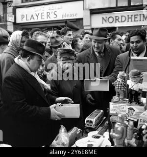 12. DEZEMBER 1962 - WEIHNACHTSEINKÄUFE AN EINEM SPIELZEUGSTAND IN PETTICOAT LANE, LONDON, ENGLAND. Stockfoto