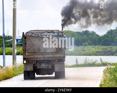 Eine beladene Lkw-Fahrt auf der Straße mit dickem, schwarzem Rauch aus dem Auspuff Stockfoto