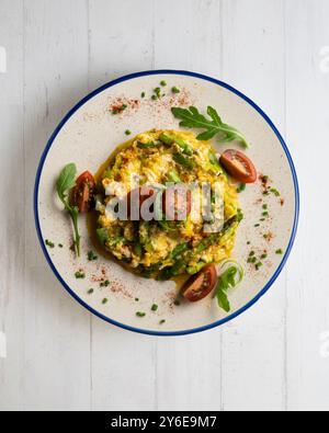 Rührei aus biologischem Anbau mit grünem Spargel und Tomaten. Tisch mit Draufsicht und Dekoration. Stockfoto