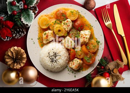 Weißfischeintopf mit Lauch und Kirschtomaten, serviert mit Reis. Tisch mit Panoramablick und Weihnachtsdekoration. Stockfoto