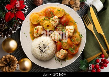 Weißfischeintopf mit Lauch und Kirschtomaten, serviert mit Reis. Tisch mit Panoramablick und Weihnachtsdekoration. Stockfoto