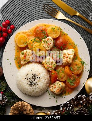 Weißfischeintopf mit Lauch und Kirschtomaten, serviert mit Reis. Tisch mit Panoramablick und Weihnachtsdekoration. Stockfoto