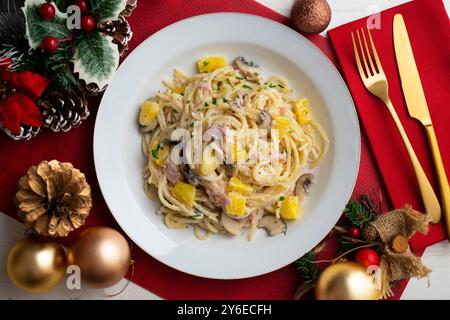 Spaghetti mit Ananas, Schinken und Sahnesauce. Tisch mit Panoramablick und Weihnachtsdekoration. Stockfoto