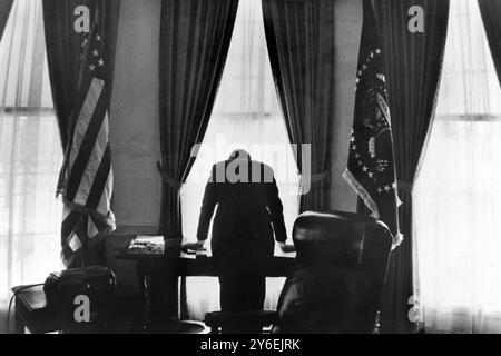 DER AMERIKANISCHE PRÄSIDENT JOHN F. KENNEDY LEHNT SICH ÜBER SEINEN SCHREIBTISCH IM WEISSEN HAUS IN WASHINGTON DC, USA. 1961 Stockfoto