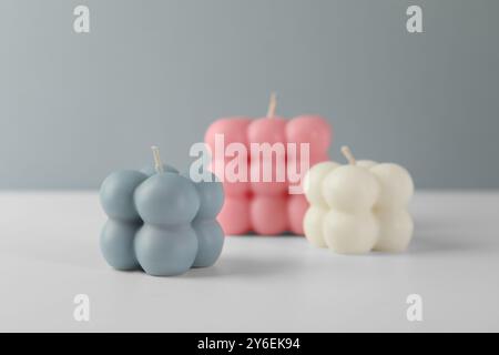 Schöne Bubble Kerzen auf weißem Tisch vor grauem Hintergrund Stockfoto