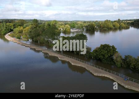 Die Leute laufen entlang der Carlton Road in Harrold, Bedfordshire, da sie nach dem Platzen des Flusses Great Ouse für Fahrzeuge gesperrt war. Für Donnerstag wurde eine gelbe Wetterwarnung für mehr starken Regen ausgegeben, als sich Großbritannien von Sturzfluten erholt, bei denen Häuser beschädigt und Reisen unterbrochen wurden. Bilddatum: Mittwoch, 25. September 2024. Stockfoto