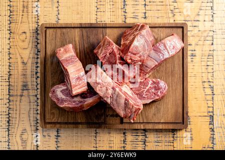 Verschiedene rohe Rindfleischstücke auf einem rustikalen Holzschneidebrett. Nahaufnahme frischer, marmorierter Fleischstücke, bereit für die kulinarische Zubereitung. Ideal für aber Stockfoto