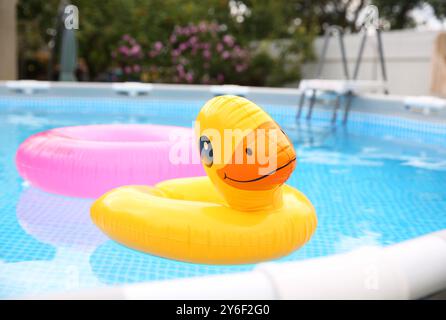 Aufblasbare Ringe, die auf dem Wasser im überirdischen Swimmingpool im Freien schwimmen Stockfoto