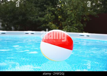 Aufblasbarer Ball schwimmt auf dem Wasser im oberirdischen Swimmingpool im Freien Stockfoto