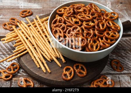 Leckere Brezel Cracker und salzige Sticks auf Holztisch, Nahaufnahme Stockfoto