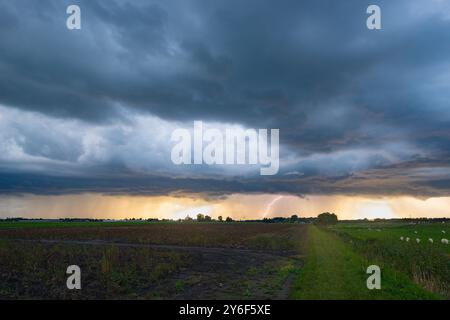 Ein Blitz trifft während des Sonnenuntergangs von einer dunklen Sturmwolke auf die Erde Stockfoto