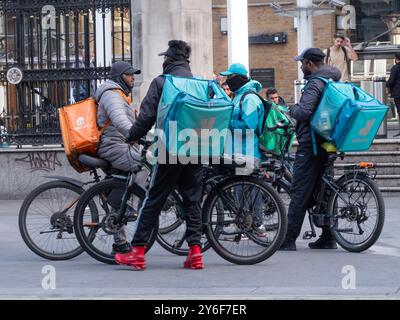 Einfach essen und Deliveroo Essenskuriere E-Bikes versammeln sich vor der Mittagszeit am Bahnhof Liverpool Street Stockfoto