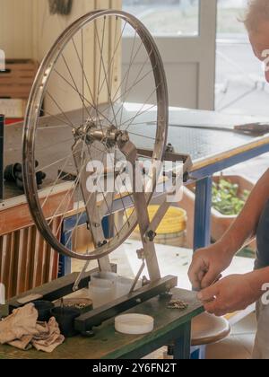 Ein erfahrener Fahrradmechaniker stellt in einer gemütlichen Werkstatt ein Rad auf und zeigt Präzision und Handwerkskunst bei der Reparatur von Fahrrädern Stockfoto