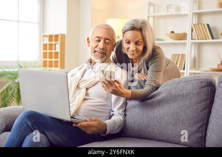 Seniorenpaare Verbringen Freizeit Zu Hause Mit Laptop Und Telefon Stockfoto