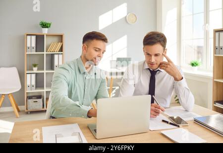 Männliche glückliche Büropartner in der Unternehmensberatung, Geschäftsmann, der am Schreibtisch mit Laptop arbeitet Stockfoto