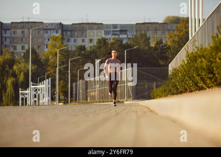 In den Straßen der Stadt mit grünen Bäumen und Gebäuden sportliche Frau laufen Workout Gesundheit Fitness. Bewegung des gesunden Lebensstils Selbstverbesserung gut Stockfoto