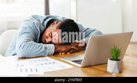 Überarbeitet afrikanische amerikanische Mitarbeiter schlafen am Arbeitsplatz im Büro Stockfoto